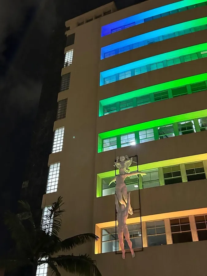 Escultura de gran formato instalada e iluminada en la fachada de un edificio de noche